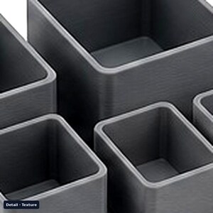 May include: A set of four dark gray square containers with a visible horizontal lined texture on the exterior walls. The containers are open at the top, featuring thick, rounded edges and a hollow interior space for storage or organization.