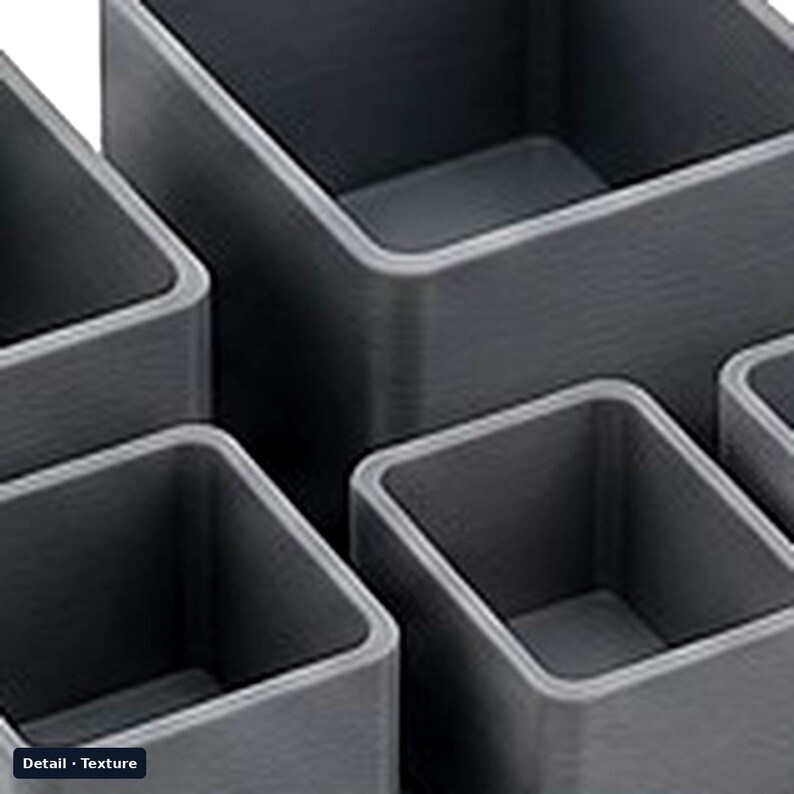 May include: A set of four dark gray square containers with a visible horizontal lined texture on the exterior walls. The containers are open at the top, featuring thick, rounded edges and a hollow interior space for storage or organization.