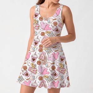 May include: White sleeveless dress with a repeating pattern of pink Mickey Mouse balloons, cookies, popcorn, and drinks. The dress has a scoop neckline and a flared skirt.