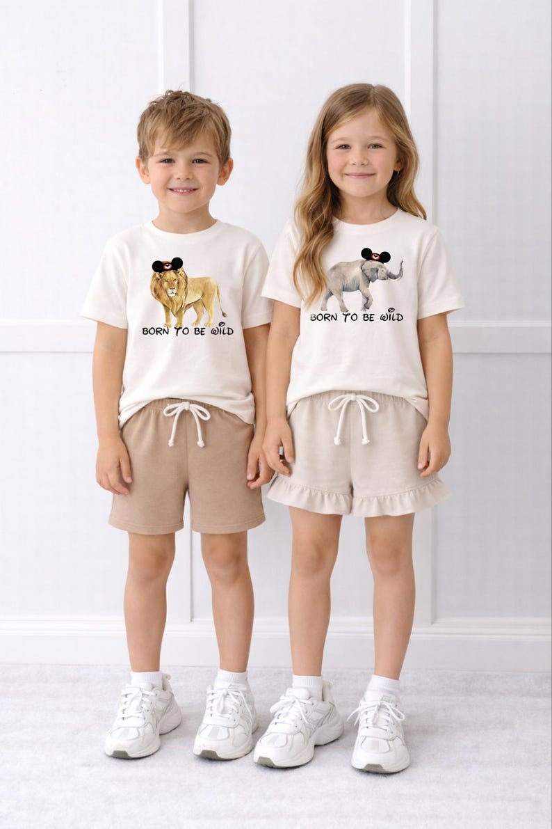 Two children wearing matching white t-shirts with animal designs and the text "Born to be wild" printed on them.