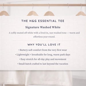 a collection of white t-shirts hanging on a wooden hanger, with a sign providing information about the t-shirts.