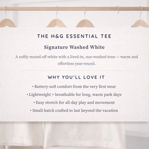 a collection of white t-shirts hanging on a wooden hanger, with a sign providing information about the t-shirts.