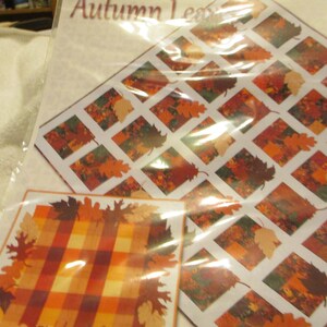 May include: A quilting pattern featuring a checkered background with autumn leaves in shades of orange, brown, and red. The pattern is titled "Autumn Leaves".
