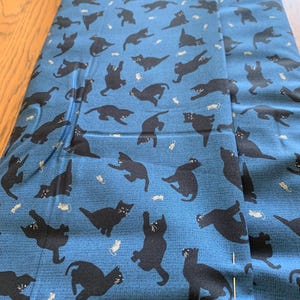 Clothworks cotton fabric Perfection with black cats on a blue background suitable for Halloween