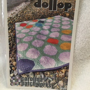 May include: A quilt pattern named "Dollop" with a design of large, irregular circles in purple, red, orange, and blue on a green background. The pattern is from Carolina Patchworks, no. 043.