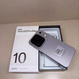 以下が含まれることがあります： 白い販売用ボックスの上に置かれたライトグレーのOppo Find X10 Pro Maxスマートフォン。ボックスにはFind X10 Pro Maxの文字、数字の10、Oppo Hasselbladのブランド名が記載されています。本体には大きなカメラモジュールと白いステッカーが貼られています。