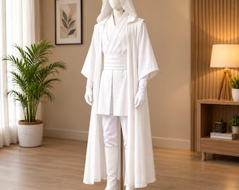 Pode incluir: Um conjunto de túnica branca com capuz num manequim, composto por uma capa comprida sem mangas, uma túnica estilo cruzado com uma faixa larga na cintura, calças brancas a condizer, luvas brancas e botas brancas até ao joelho.