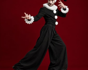 May include: A black and white jester costume featuring a long-sleeved black top with three large white buttons, wide-leg black trousers, and a pleated white ruff collar and cuffs. A matching two-toned jester hat with black and white pom-poms.