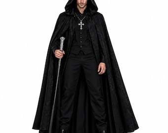 Pode incluir: Uma capa preta com capuz usada sobre um colete, camisa e calças pretas. O conjunto inclui um pingente de cruz prateada numa corrente e uma bengala com punho prateado. A capa apresenta um padrão subtil tom sobre tom em todo o tecido.