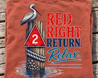 May include: A rust-colored t-shirt featuring a graphic of a pelican perched on a wooden piling with a red triangular sign marked with the number 2. The text reads RED RIGHT RETURN. Relax. LOW KEY LIVING in a distressed, weathered font style.