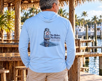 May include: A light blue long-sleeve hooded shirt featuring a graphic on the back of a wooden piling with a sign that reads "Idle Speed" and "No Wake. No Hurry. Low Key Living" with a rope wrapped around the base of the post.