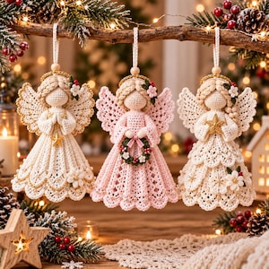 May include: Three crocheted angel ornaments hanging from a branch. The left angel is cream with a gold star, the center is pink holding a wreath, and the right is cream with a gold star. Each features braided hair, a halo, and intricate lace skirts.