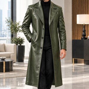 May include: A long, olive green leather trench coat featuring a notched lapel, a three-button front closure, and two side pockets. The coat is worn over a black turtleneck sweater and black trousers, paired with black leather boots and sunglasses.