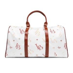 May include: A white duffel bag featuring a repeating pattern of the letters LB in shades of red and tan, accented with small four-pointed star symbols. The bag includes brown leather-like trim, two matching top handles, and a gold-toned zipper.