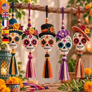 Puede incluir: Cinco adornos de calavera tejidos a ganchillo colgados de una rama. Cada calavera presenta bordados de hilo de colores, detalles florales o sombreros, y una borla decorativa. Las calaveras son blancas con patrones en naranja, azul, rosa y morado.