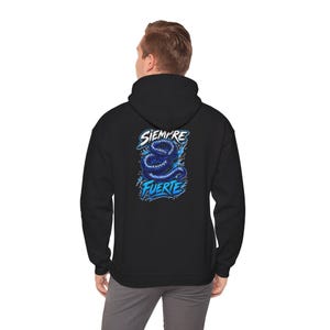 Könnte beinhalten: Ein schwarzer Kapuzenpullover mit einer Grafik auf der Rückseite, die eine zusammengerollte dunkelblaue Schlange mit hellblauen Akzenten zeigt. Der Text SIEMPRE steht in Weiß über der Schlange und FUERTE in Hellblau unter der Schlange.