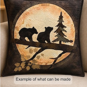 May include: A square throw pillow featuring a quilted design of two black bears perched on a tree branch next to a pine tree, set against a circular cream and orange background with swirl patterns. The text "Example of what can be made" is visible.