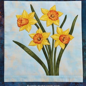 Könnte beinhalten: Stoffpaneel mit einem Narzissen-Design. Die Narzissen haben gelbe Blütenblätter und orangefarbene Zentren, mit grünen Stielen und Blättern. Der Hintergrund ist hellblau mit einem Aquarelleffekt. Der Text "Example of what can be made" steht unten.