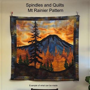 Könnte beinhalten: Eine Steppdecke, die eine Bergszene mit einem Sonnenuntergangshimmel, Bäumen und einem Berggipfel darstellt. Die Steppdecke trägt den Titel "Spindles and Quilts Mt Rainier Pattern" und ist ein Beispiel dafür, was mit dem Muster hergestellt werden kann.