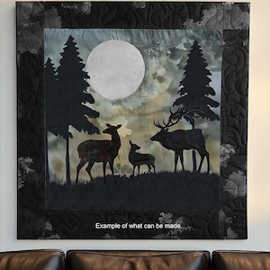 May include: A framed quilt featuring a nighttime forest scene with elk and fawns under a full moon. The quilt has a black border and the text "Spindles and Quilts Elk and Fawns Pattern" is at the top. The phrase "Example of what can be made" is at the bottom.