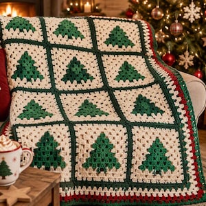 May include: A crochet blanket featuring a grid of cream-colored squares, each containing a green Christmas tree motif, bordered by dark green yarn. The blanket is draped over a sofa next to a red pillow with the text Merry Christmas.