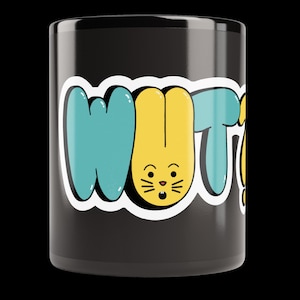 Può includere: Una tazza in ceramica nera con un design grafico che riporta il testo WUT in grandi lettere in stile bolla. La lettera U è gialla e ha la forma di un muso di coniglio sorpreso con i baffi, mentre la W e la T sono di colore blu ottanio.