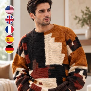 May include: A long-sleeved crochet jumper featuring a colour-blocked geometric pattern in shades of black, cream, and burnt orange. The garment has a crew neckline and ribbed cuffs, constructed with a visible textured yarn stitch throughout.