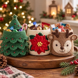 May include: Three crocheted containers filled with assorted candies. One is a green Christmas tree with red beads, one is cream-colored with a red poinsettia, and one is a brown reindeer with antlers and ears, all sitting on a wooden tray.