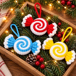 Könnte beinhalten: Drei gehäkelte Bonbon-Ornamente in Rot, Blau und Gelb, jeweils mit weißem Spiralmuster und weißen, gerüschten Rändern. Jedes Ornament verfügt über eine passende Garnschlaufe zum Aufhängen und eine strukturierte Garnverarbeitung.