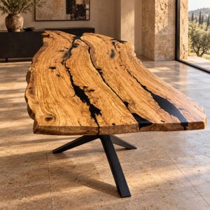 May include: A dining table featuring a live-edge light brown wood slab surface with prominent natural grain patterns and deep black resin inlays filling the central fissures. The table is supported by a black metal base with four angled legs.