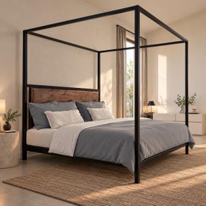 Op de afbeelding: Een hemelbedframe van zwart metaal met een rechthoekige structuur en een donkerbruin houten hoofdeinde. Het bed is opgemaakt met een wit hoeslaken, een grijs dekbed, twee grote grijze kussens en twee kleinere witte rechthoekige kussens.
