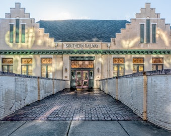 May include: A brick building with a white facade and a green awning. The building has a sign that reads "SOUTHERN RAILWAY". There is a brick walkway leading to the entrance of the building.