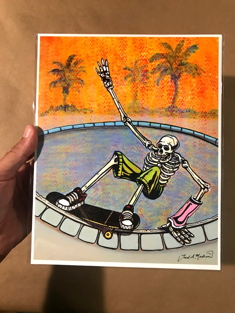 Pu&ograve; includere: Uno scheletro con pantaloncini verdi e gomitiere rosa sta facendo skateboard in una piscina. La piscina &egrave; circondata da un bordo di piastrelle blu e bianche. Lo sfondo &egrave; un tramonto con palme.