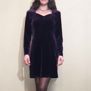 May include: A purple velvet dress with a square neckline and long sleeves.
