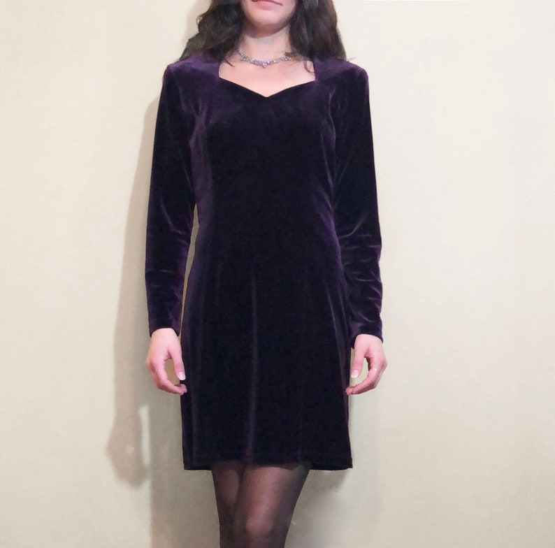May include: A purple velvet dress with a square neckline and long sleeves.