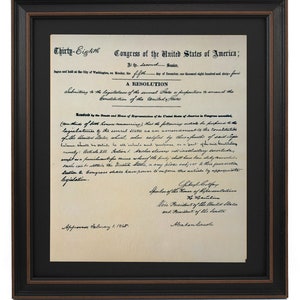 May include: A historical document, the 13th Amendment to the United States Constitution, signed by Abraham Lincoln, abolishing slavery. The document is framed in a black and brown frame.