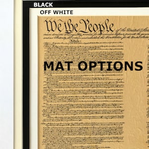 May include: A framed document with the text "We the People" of the United States Constitution. The document is on a cream background with black text. The frame is black with a white mat.