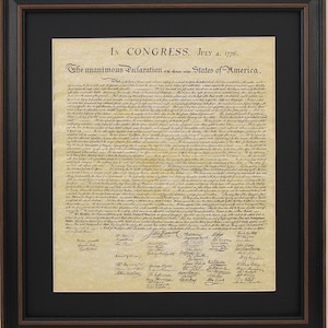 May include: A framed print of the Declaration of Independence, signed by the founding fathers. The document is written in cursive script on aged parchment paper. The text reads "In Congress, July 4, 1776. The unanimous Declaration of the thirteen united States of America."