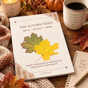 Może przedstawiać: Książka w miękkiej oprawie zatytułowana The Autumn Reset Write Reflect Grow z kremową okładką, ilustracją zielonego i żółtego liścia klonu, tekstem o zwalnianiu tempa oraz ozdobną ramką z małymi gwiazdkami na drewnianej powierzchni.