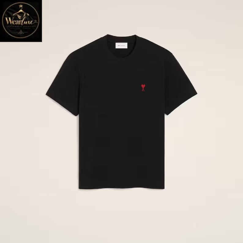May include: A black short-sleeved t-shirt featuring a crew neckline and a small red heart-shaped logo embroidered on the left chest area. The garment has a straight hemline and a clean, solid-colored design throughout the front of the piece.