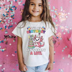 Puede incluir: Camiseta blanca con un gráfico colorido de un ajolote sosteniendo un pastel de cumpleaños. El texto en la camiseta dice "It's My Birthday Let's Party A LOTL".