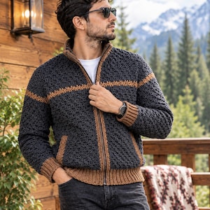 Puede incluir: Una chaqueta de ganchillo con cremallera en color gris carbón oscuro, con un patrón de puntos texturizados, cuello alto y ribetes de punto acanalado en color tostado en puños, dobladillo, tapeta de la cremallera y una franja horizontal.