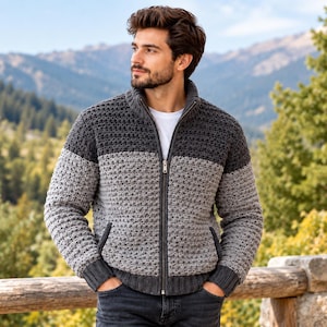 May include: A colour-blocked zip-up cardigan featuring a dark charcoal upper section and a light grey lower section. The garment has a ribbed stand-up collar, long sleeves with ribbed cuffs, a full-length metal zip, and two front pockets.