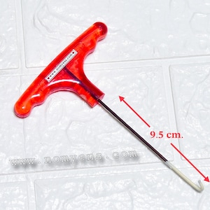 Könnte beinhalten: Ein rotes T-Griff-Werkzeug mit einem 9,5 cm langen Schaft und einem Hakenende. Der Griff trägt den Text "www.nomyens.com". Das Werkzeug ist zum Ziehen oder Einhaken bestimmt.