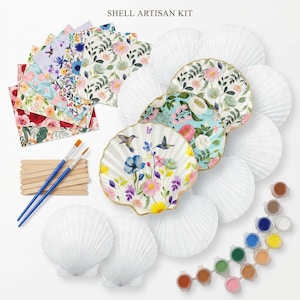 May include: A Shell Artisan Kit featuring white scallop shells, some decorated with floral and hummingbird patterns, alongside a set of paint pots, two blue-handled paintbrushes, wooden mixing sticks, and several sheets of patterned decoupage paper.