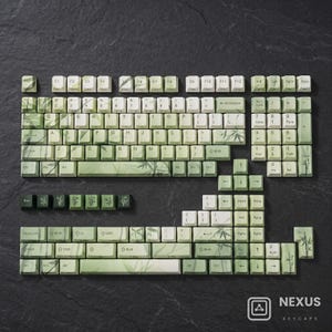 May include: A full set of mechanical keyboard keycaps featuring a light green and white bamboo leaf pattern. The set includes alphanumeric keys, function keys, a number pad, and various modifier keys, all displaying a consistent botanical theme.