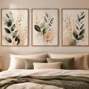 Peut inclure: Un ensemble de trois cadres muraux présentant des illustrations botaniques à l'aquarelle de feuilles et de brindilles dans des tons de vert sauge, olive et beige doux, présentés dans des cadres en bois clair sur un mur neutre.