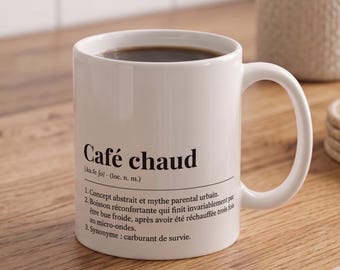 May include: A white ceramic mug filled with dark coffee, featuring black printed text that reads Café chaud, followed by a phonetic pronunciation and a humorous three-point definition in French describing the beverage as a survival fuel.