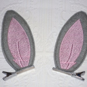 Cute grey felt bunny ear attached to ribbon lined double pronged alligator clips.