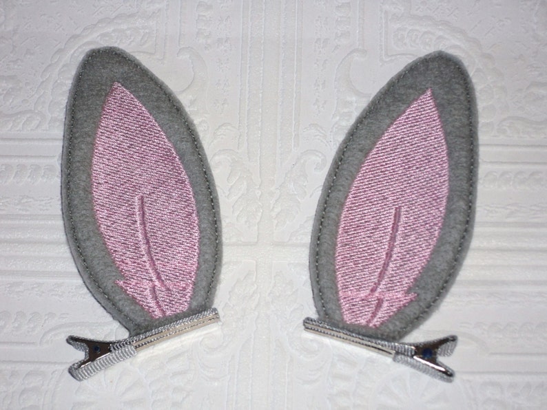 Cute grey felt bunny ear attached to ribbon lined double pronged alligator clips.